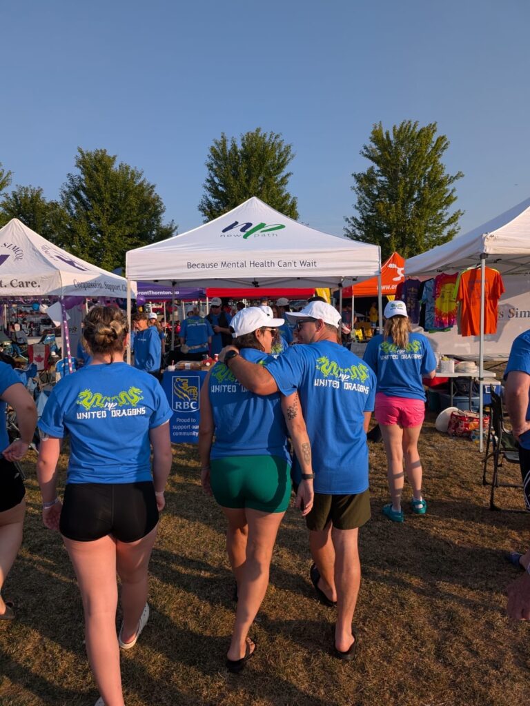 Picture of people walking. Two of the people are walking closely together with one having an arm across the others shoulder.
