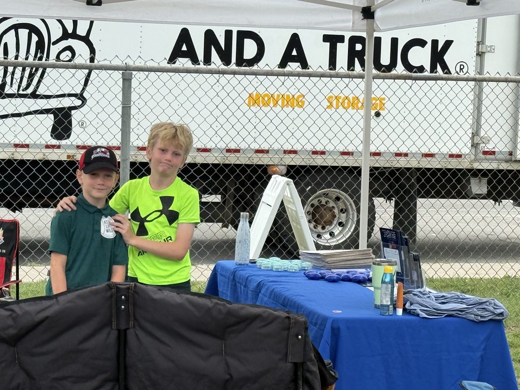 A picture of two boys at a table filled with SWAG.