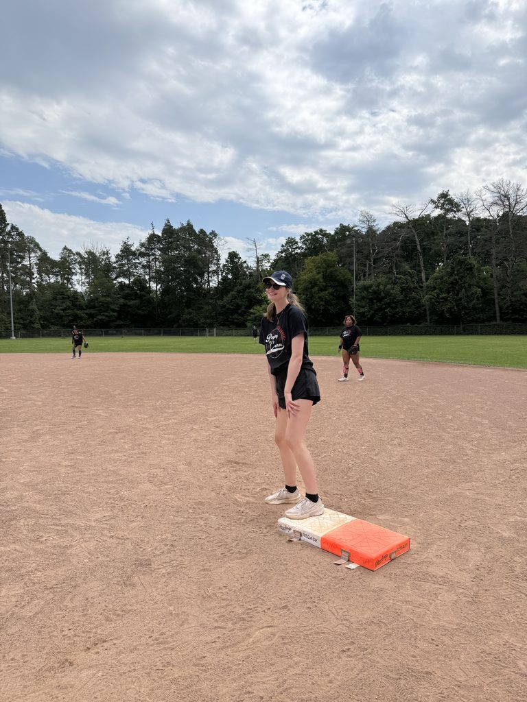 A woman standing on first base smiling. 