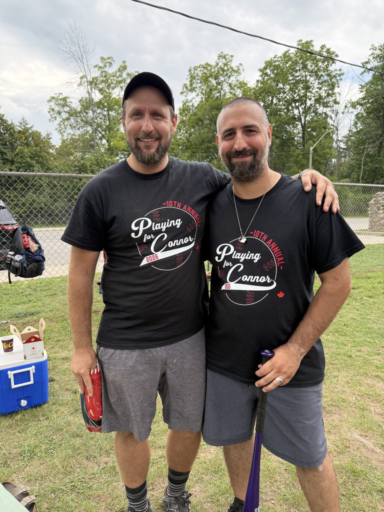 Two men wearing Playing for Connor t-shirts smiling 