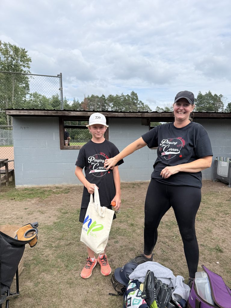 A young boy and a women smiling. The boy is holding a New Path branded bag. 