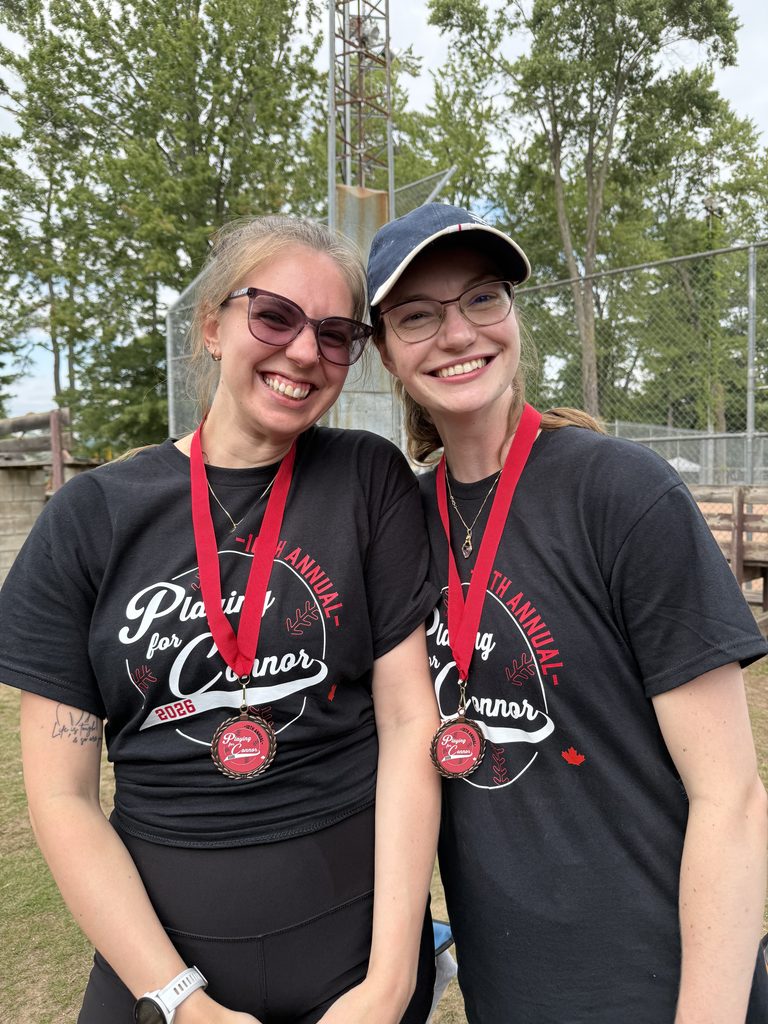 Two women wearing medals smiling.