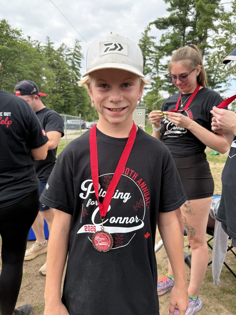 A young boy with a medal around his neck smiling 