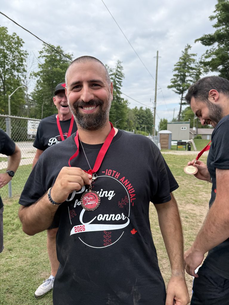 A man holding a medal and smiling. 