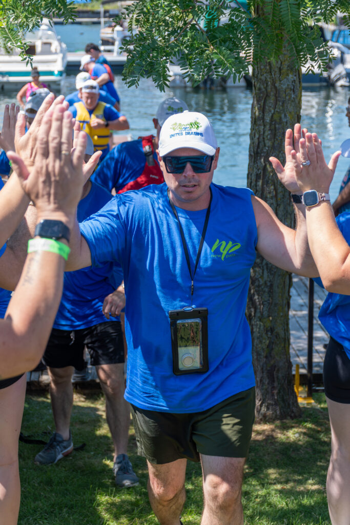 Picture of a man smiling and giving high fives to other people