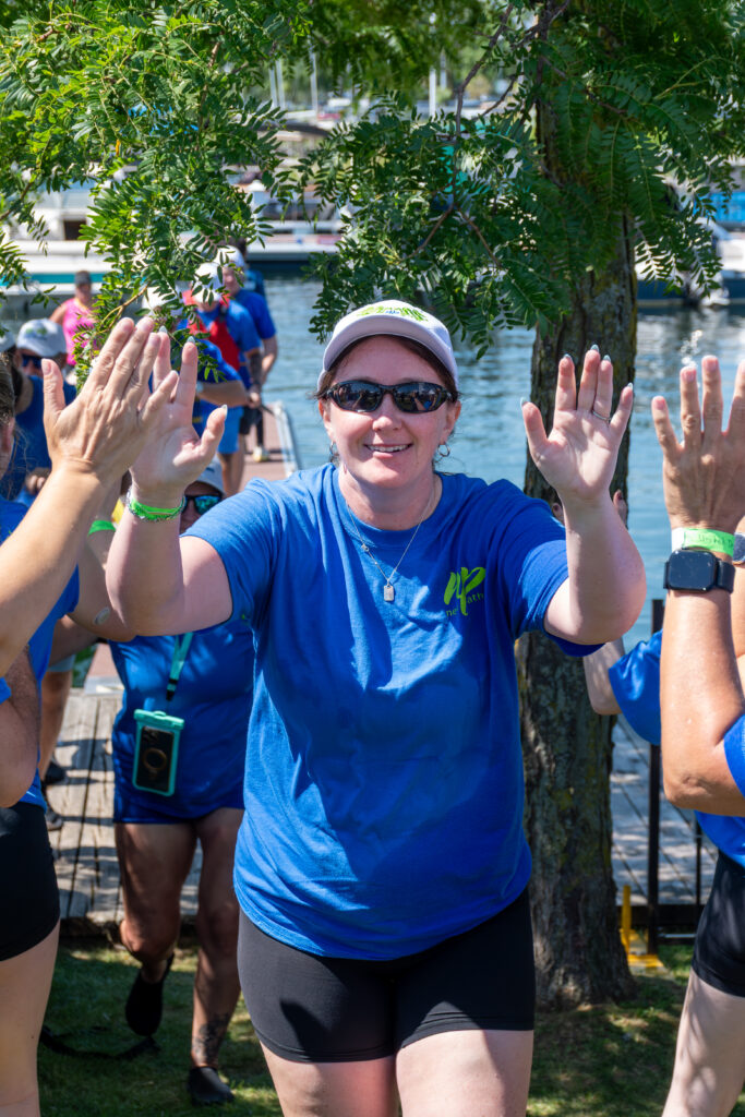 Picture of a woman smiling and giving high fives to other people