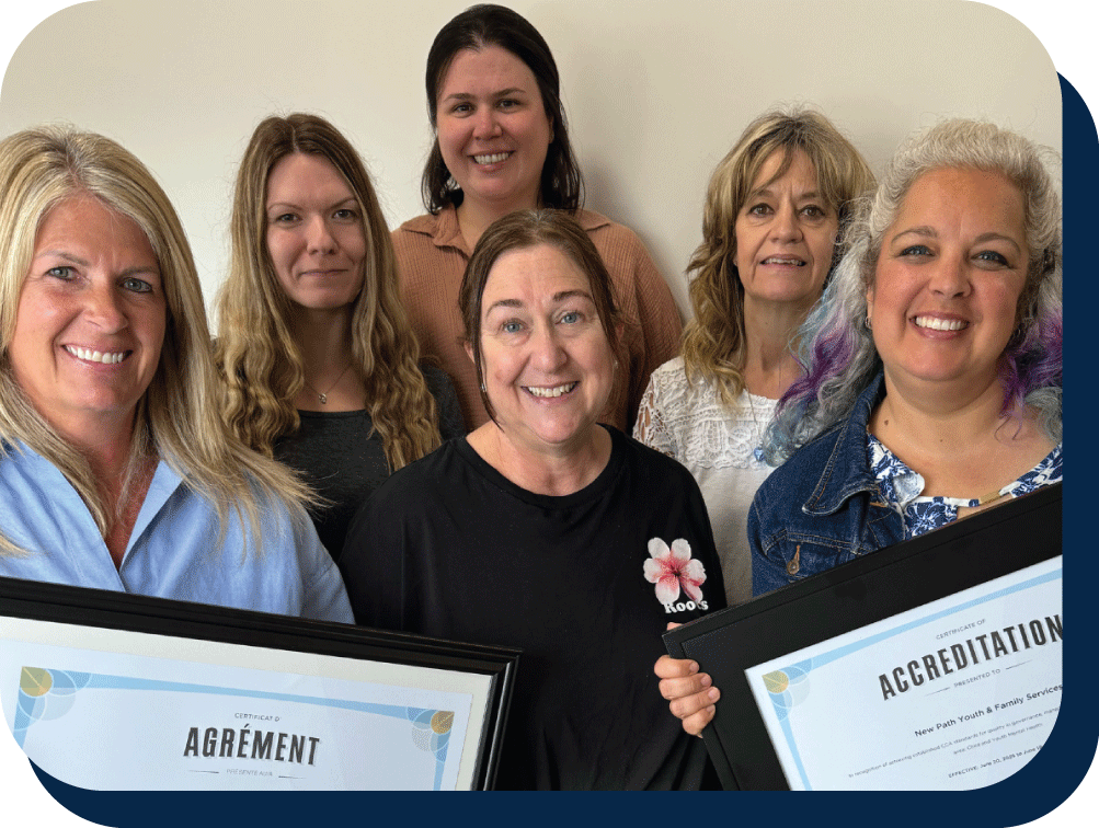 Picture of group of women smiling and holding up French and English accreditation signs.