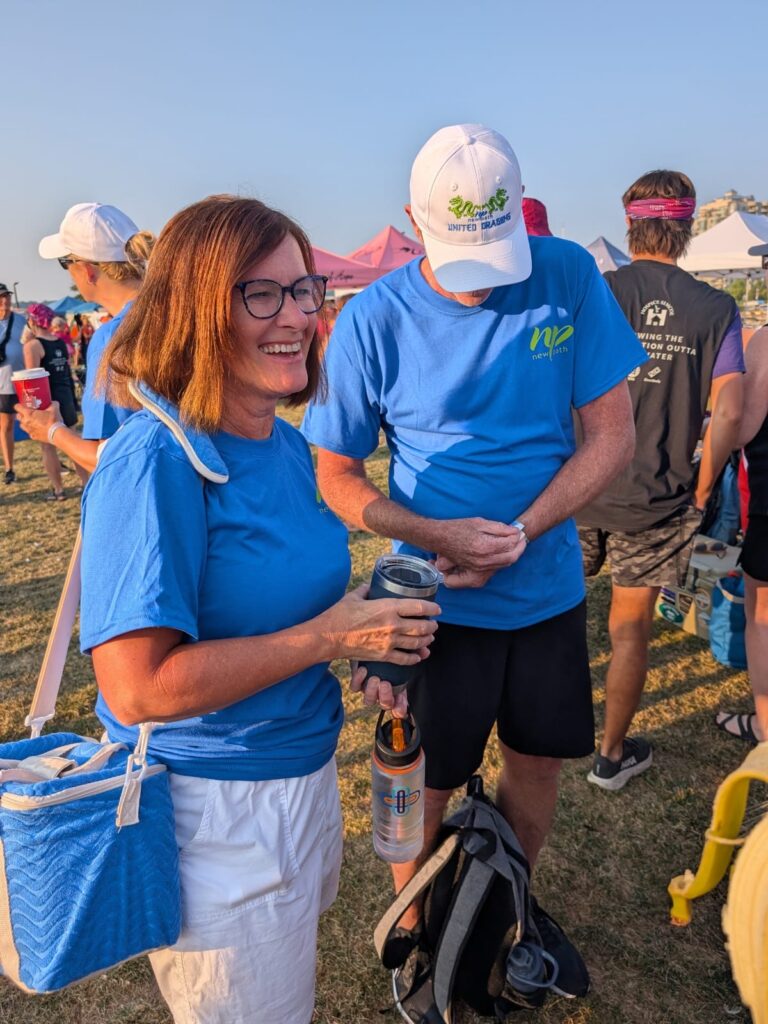 Picture of a woman smiling and a man being over to affix a wrist band.